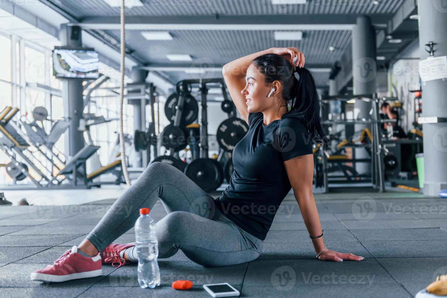Young girl in sportive clothes taking a break with food and water is in the gym at daytime photo