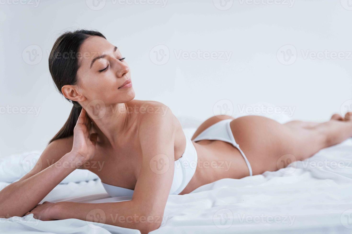 mujer joven en ropa interior y con buena forma de cuerpo acostada en el  estudio contra fondo blanco 15248669 Foto de stock en Vecteezy