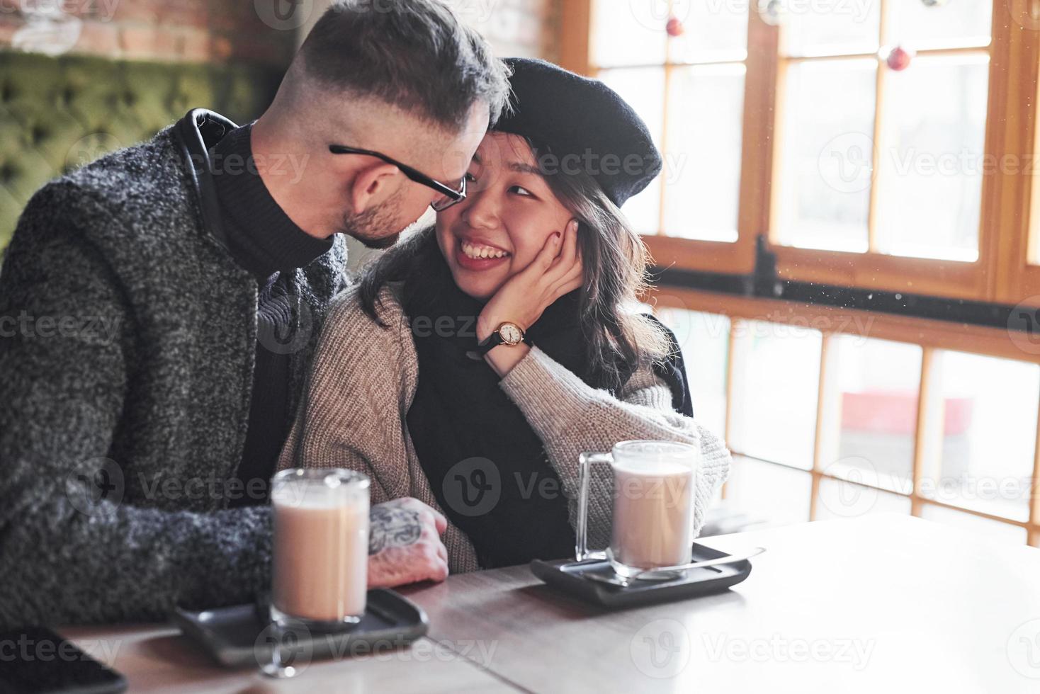 Multiracial couple talking in cafe. Asian girl with her caucasian boyfriend photo