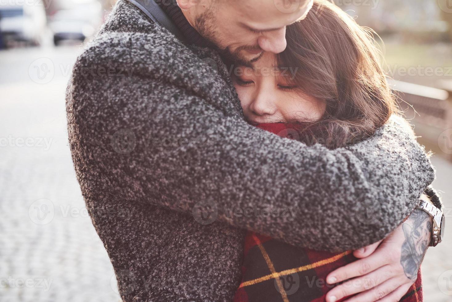 Warming by using red plaid. Happy multiracial couple together outdoors in the city. Asian girl with her caucasian boyfriend photo