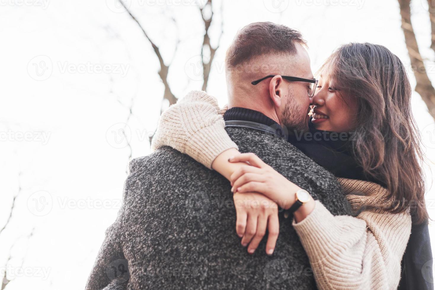 Cheerful multiracial couple embracing each other outdoors in the city. Asian girl with her caucasian boyfriend photo