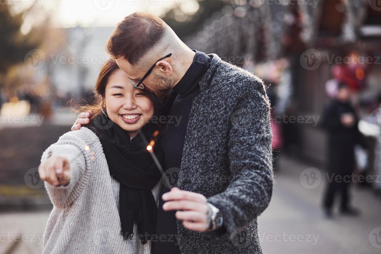 con bengalas en las manos. feliz pareja multirracial juntos al aire libre en la ciudad foto