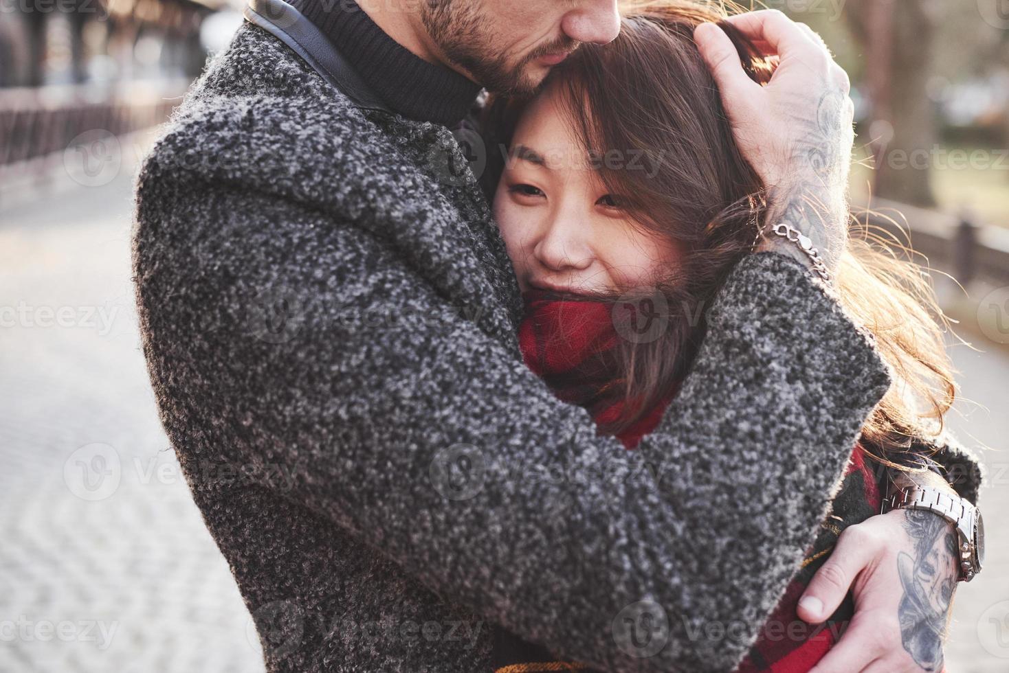 Warming by using red plaid. Happy multiracial couple together outdoors in the city. Asian girl with her caucasian boyfriend photo