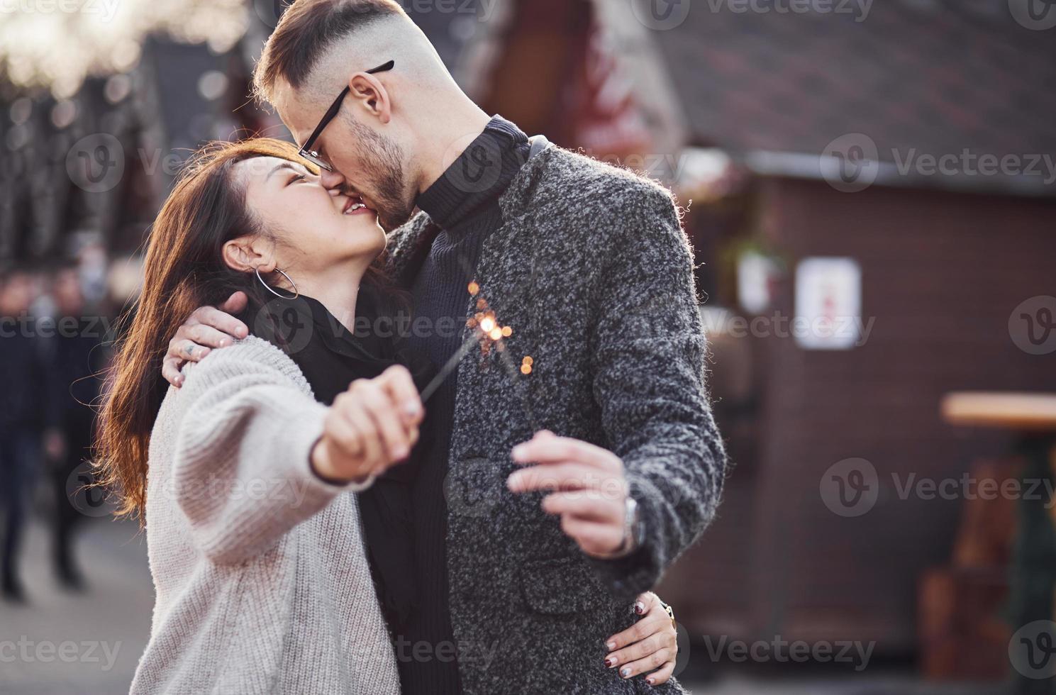 With sparklers in hands. Happy multiracial couple together outdoors in the city photo