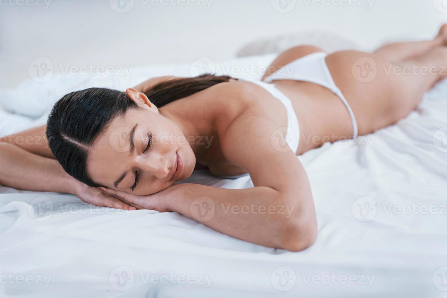 Young woman in underwear and with nice body shape lying down in the studio against white background photo