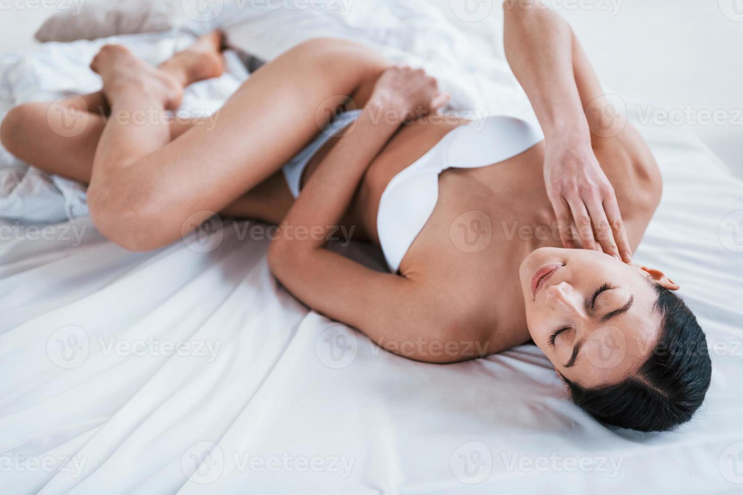 Young woman in underwear and with nice body shape lying down in the studio against white background photo