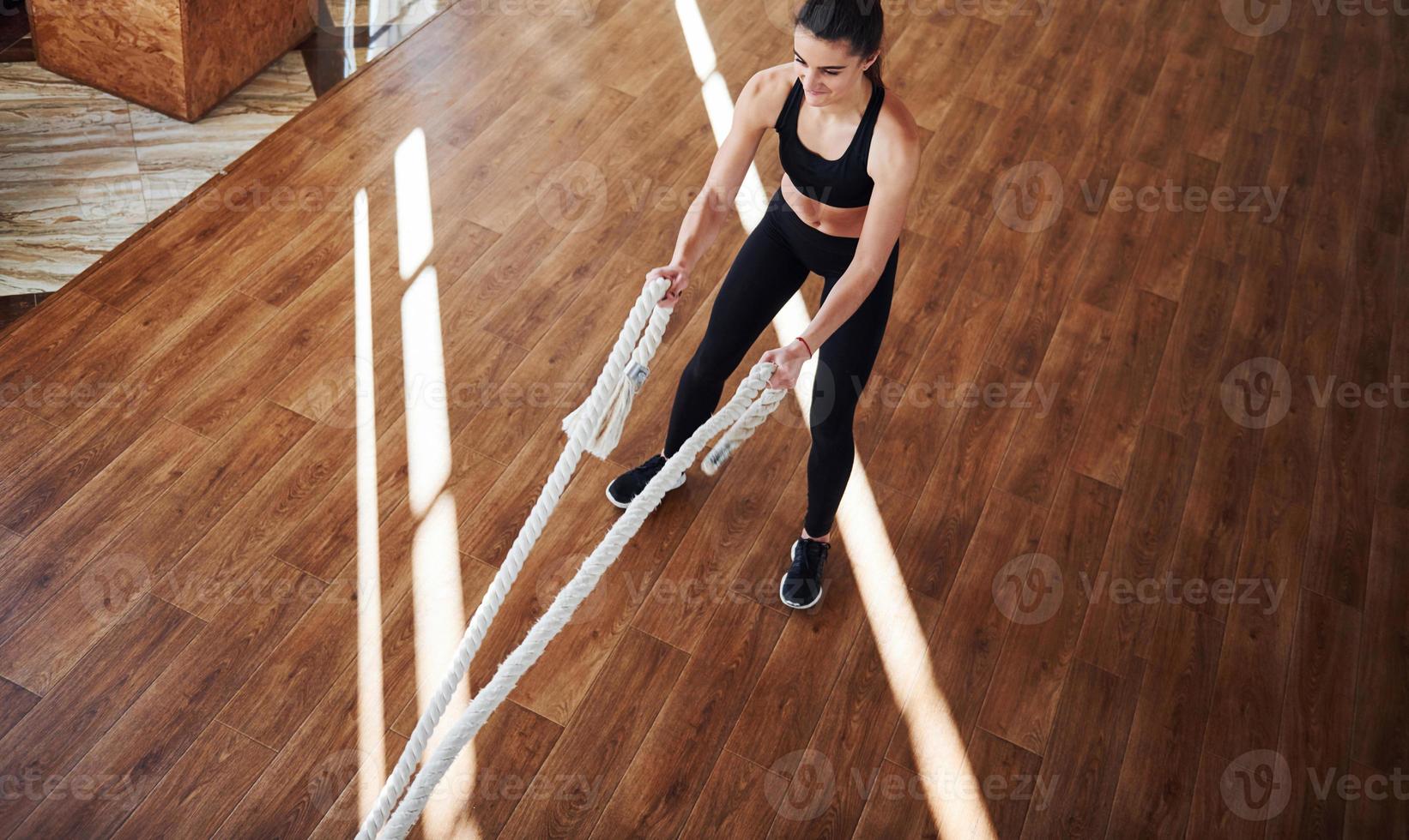 en el suelo iluminado por haces de luz. joven deportista en ropa deportiva haciendo fitness usando nudos foto