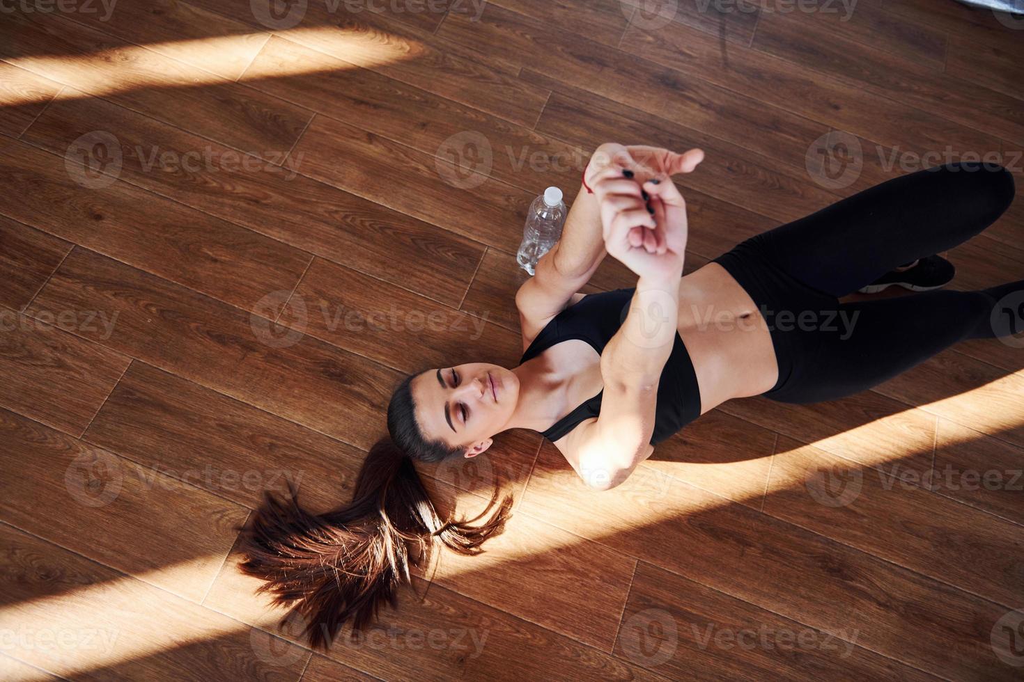 On the floor illuminated by light beams. Young sporty woman in sportswear doing fitness in the gym photo