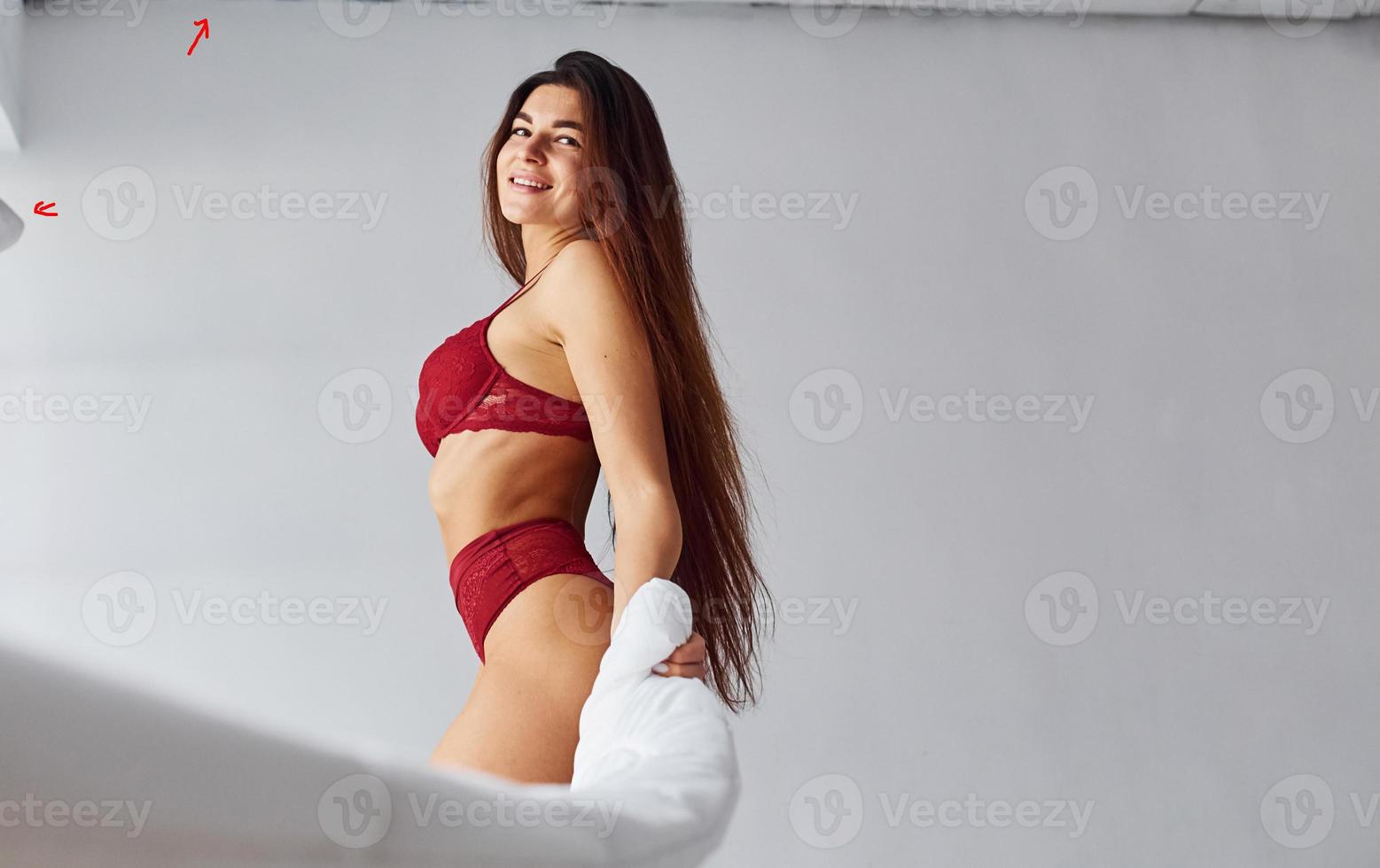 Woman in red underwear covering her body by towel in the studio against white background photo