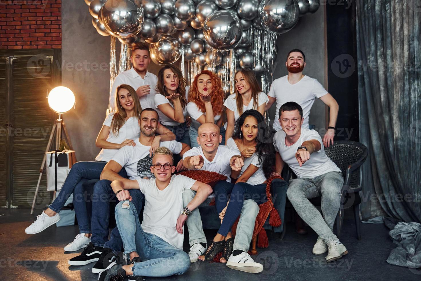 Positive young people sitting and celebrating New Year in christmas decorated room with balloons together photo