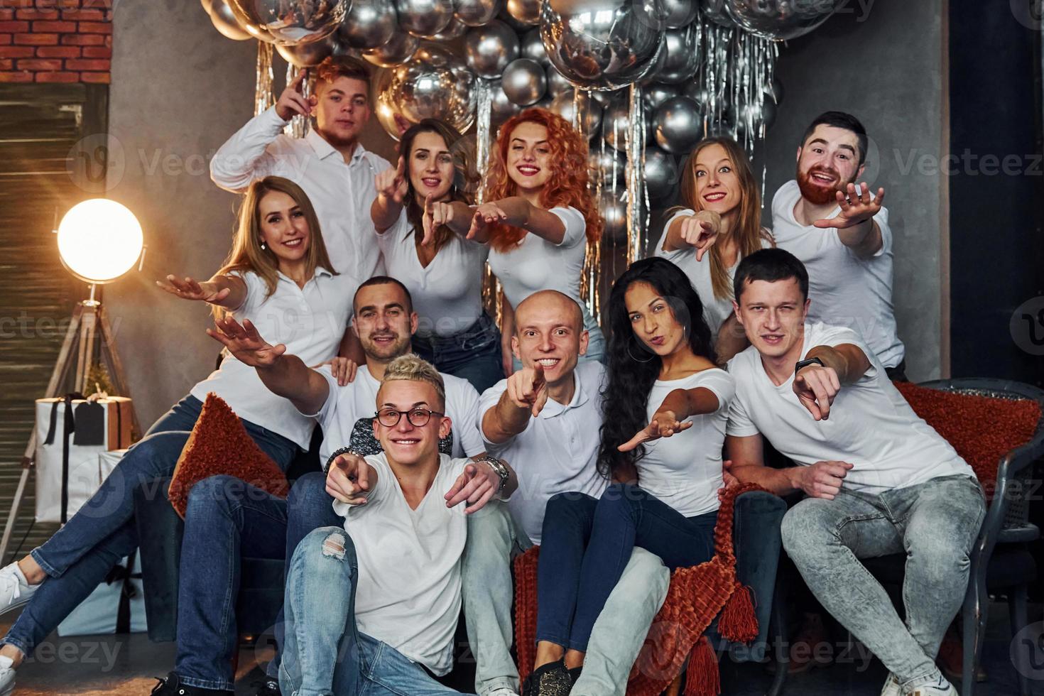 jóvenes felices celebrando el año nuevo en una habitación decorada de navidad con equipo de iluminación foto