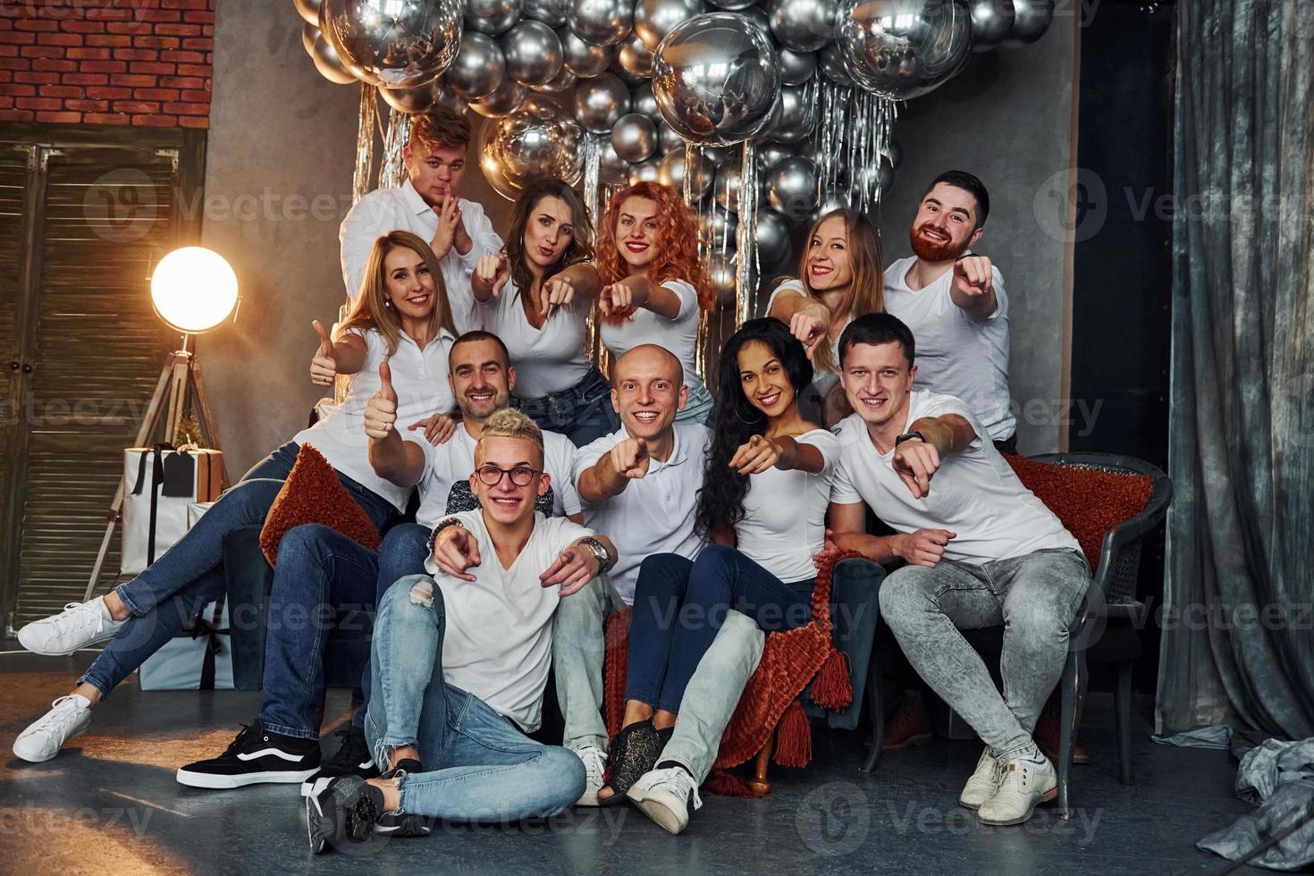 Happy young people celebrating New Year in christmas decorated room with lighting equipment photo