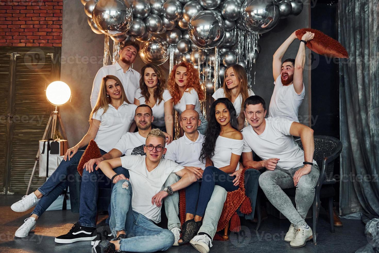 Positive young people sitting and celebrating New Year in christmas decorated room with balloons together photo