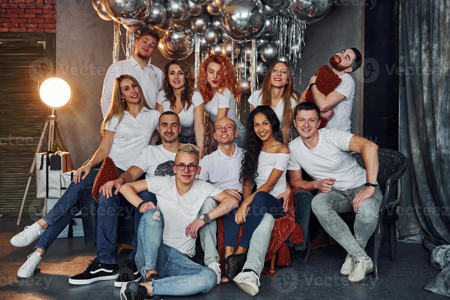 Positive young people sitting and celebrating New Year in christmas decorated room with balloons together photo