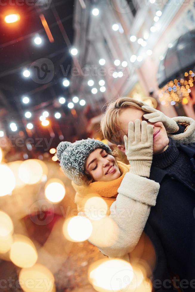 Cute young girl makes surprise to her boyfriend by walking behind him photo