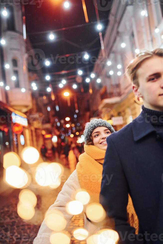 Cute young girl makes surprise to her boyfriend by walking behind him photo