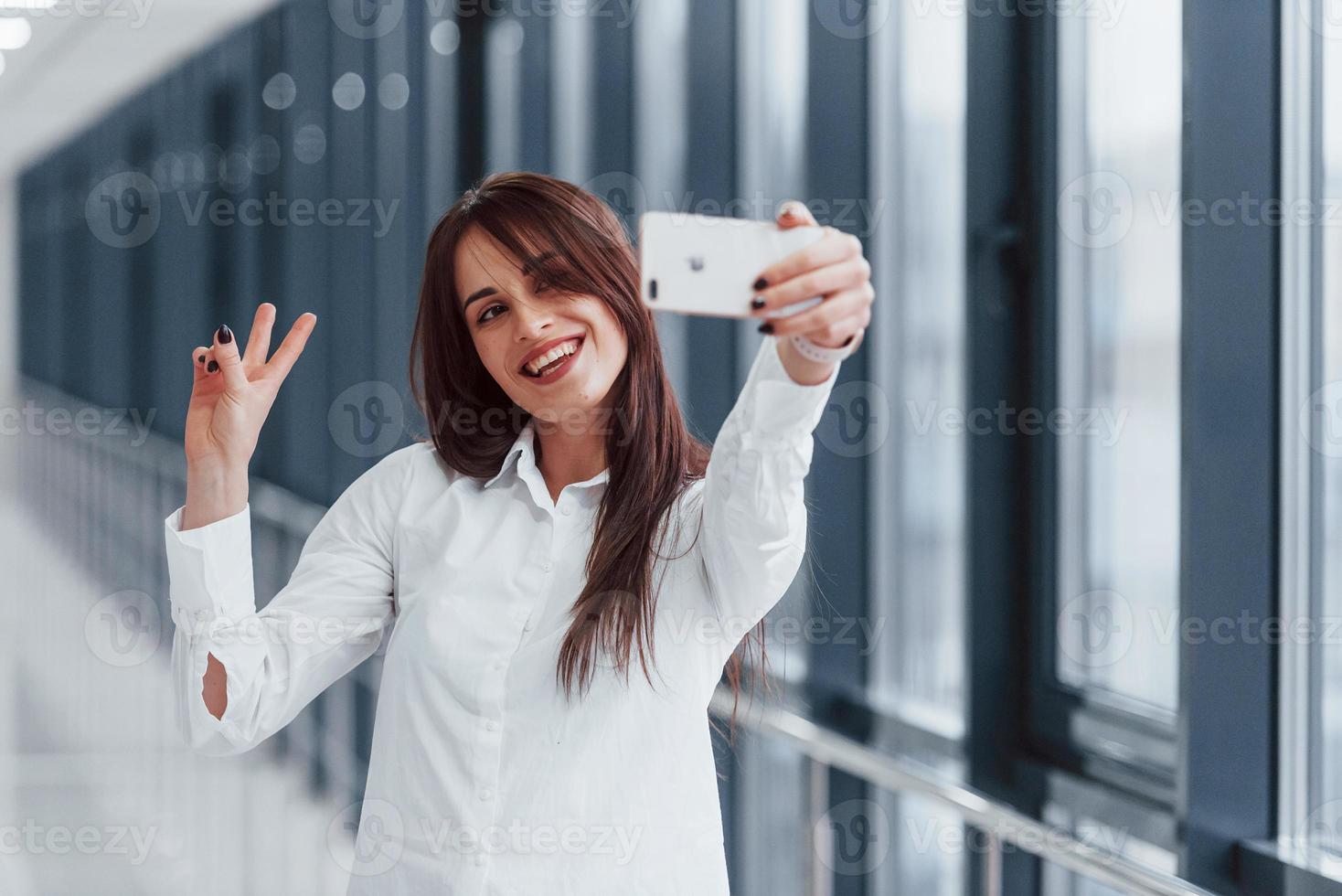 Brunette in white shirt that walks indoors in modern airport or hallway at daytime photo