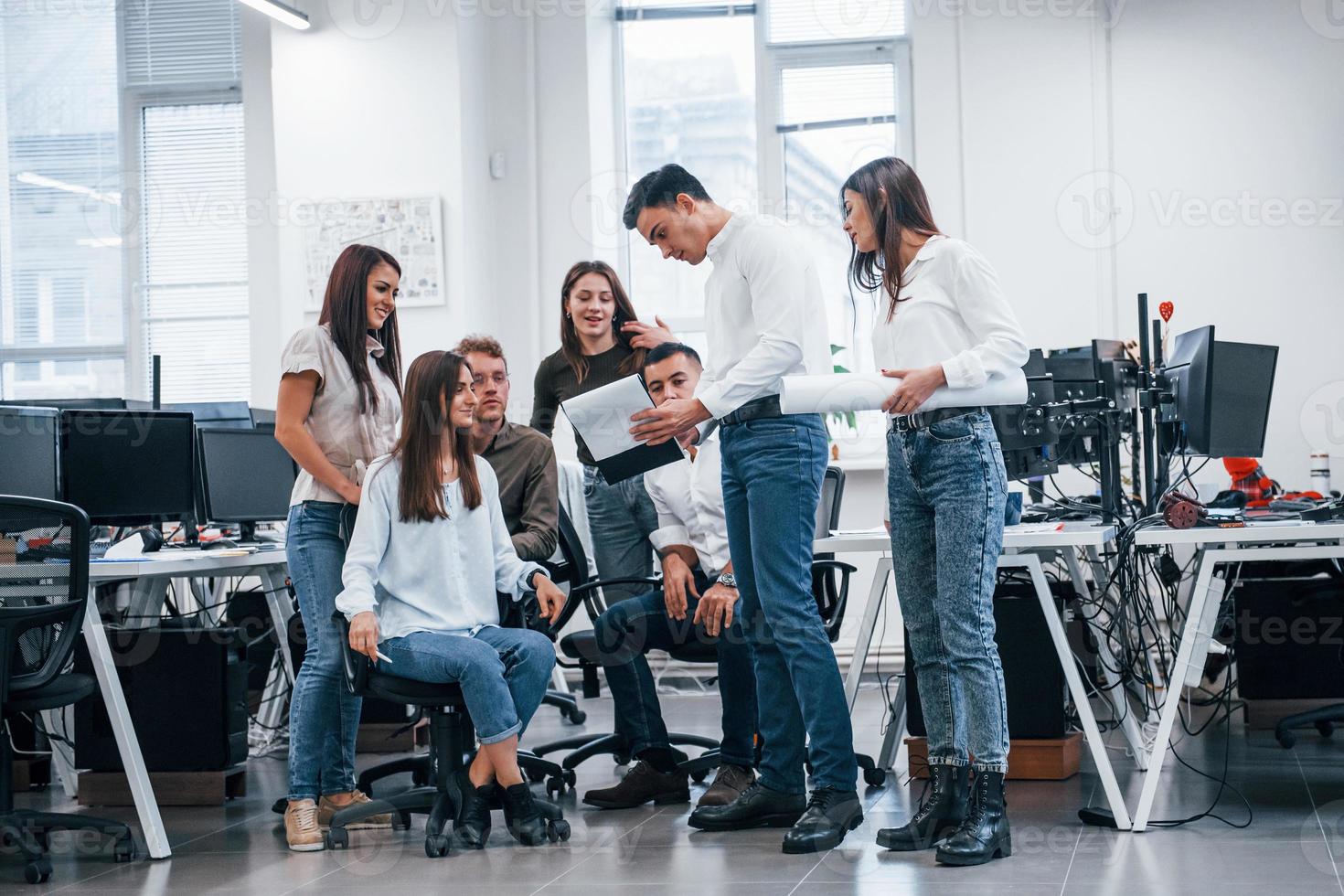 grupo de jóvenes empresarios que están de pie, sentados y trabajando en la oficina foto