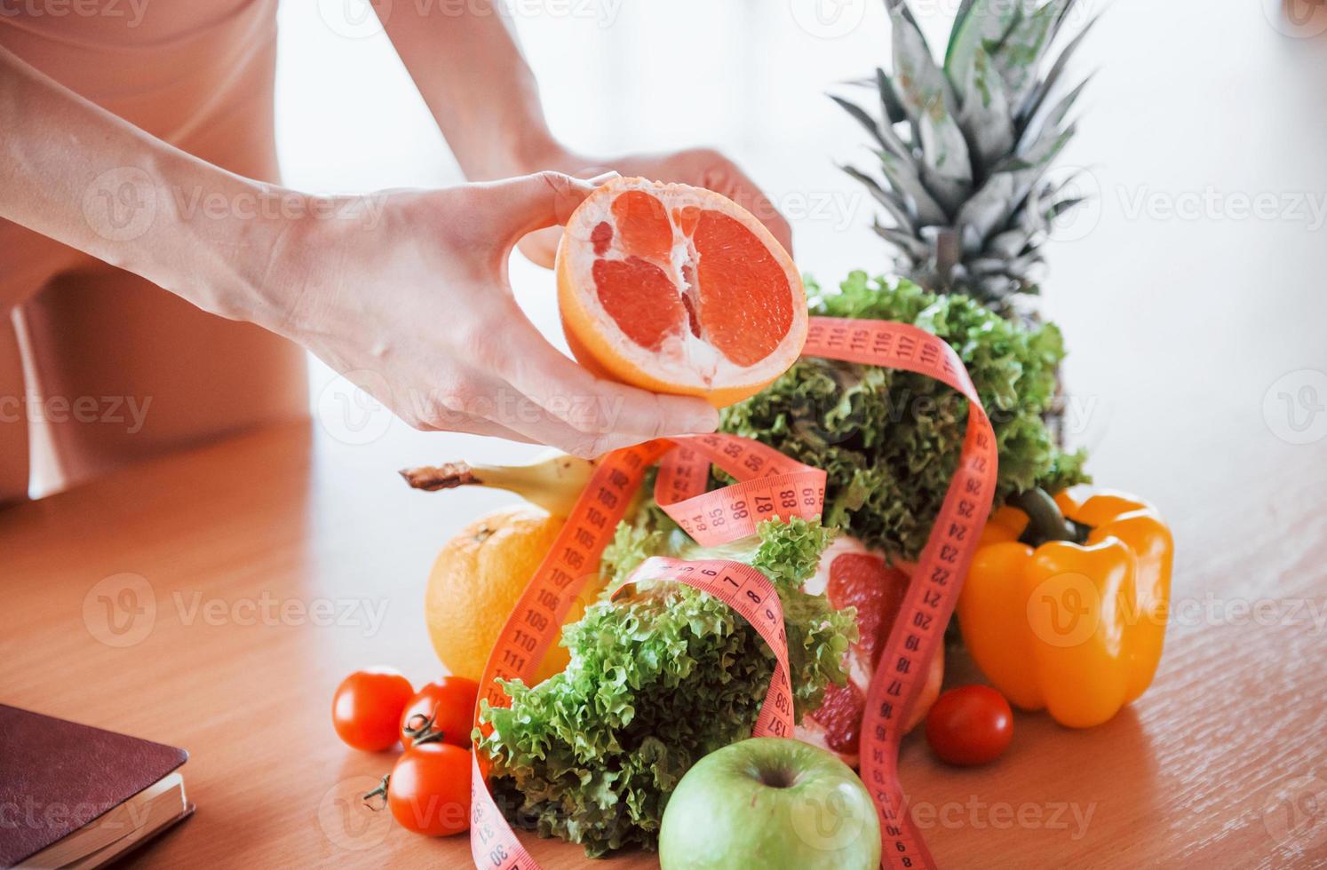 Young girl with slim body type is indoors in sportive wear near table with heatlhy food photo