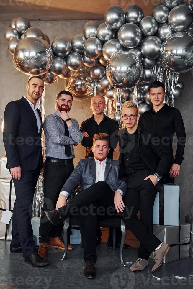 Young men in festive clothes celebrating New Year indoors of christmas decorated room together photo