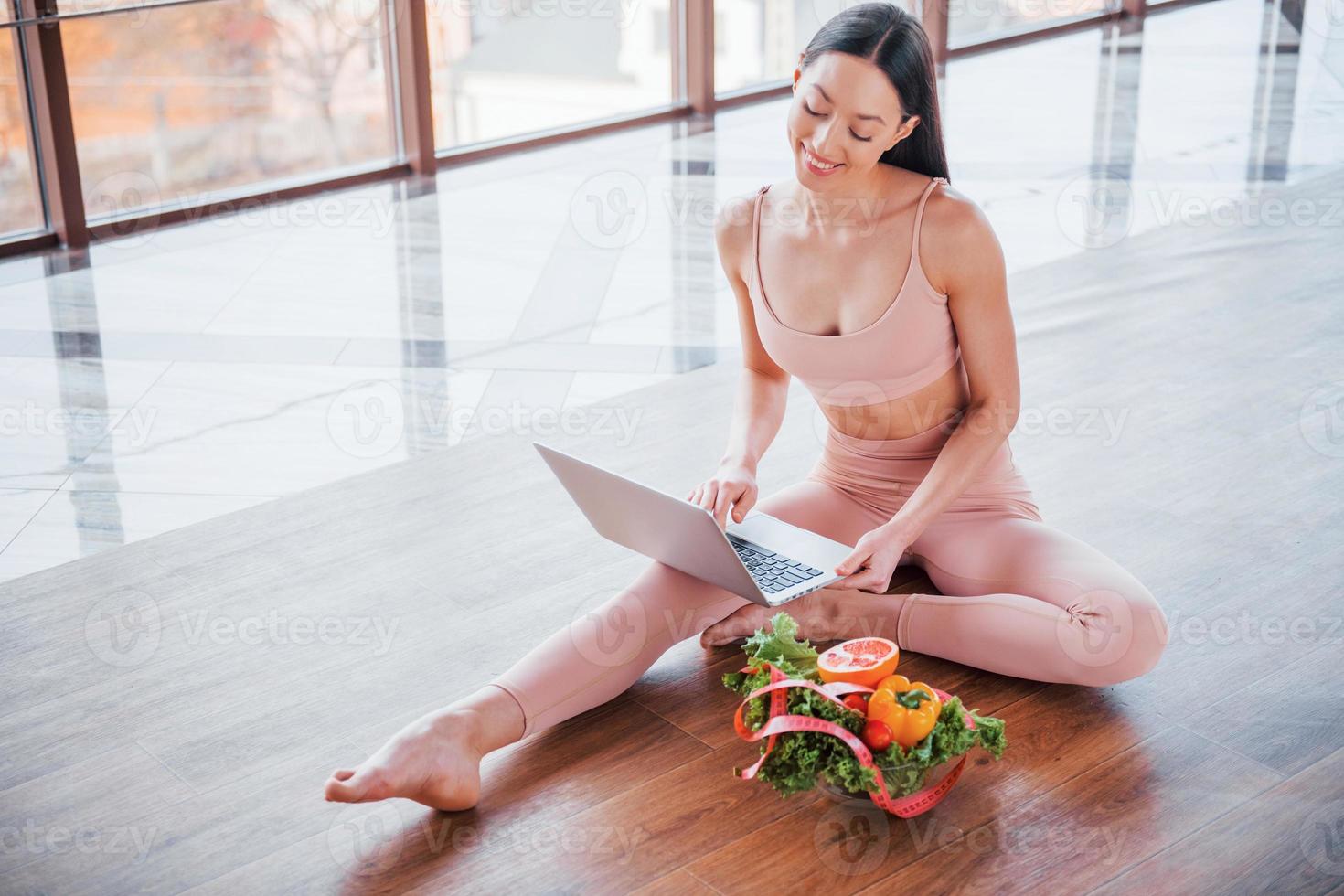 Sportive woman sitting on the table with laptop and healthy food photo