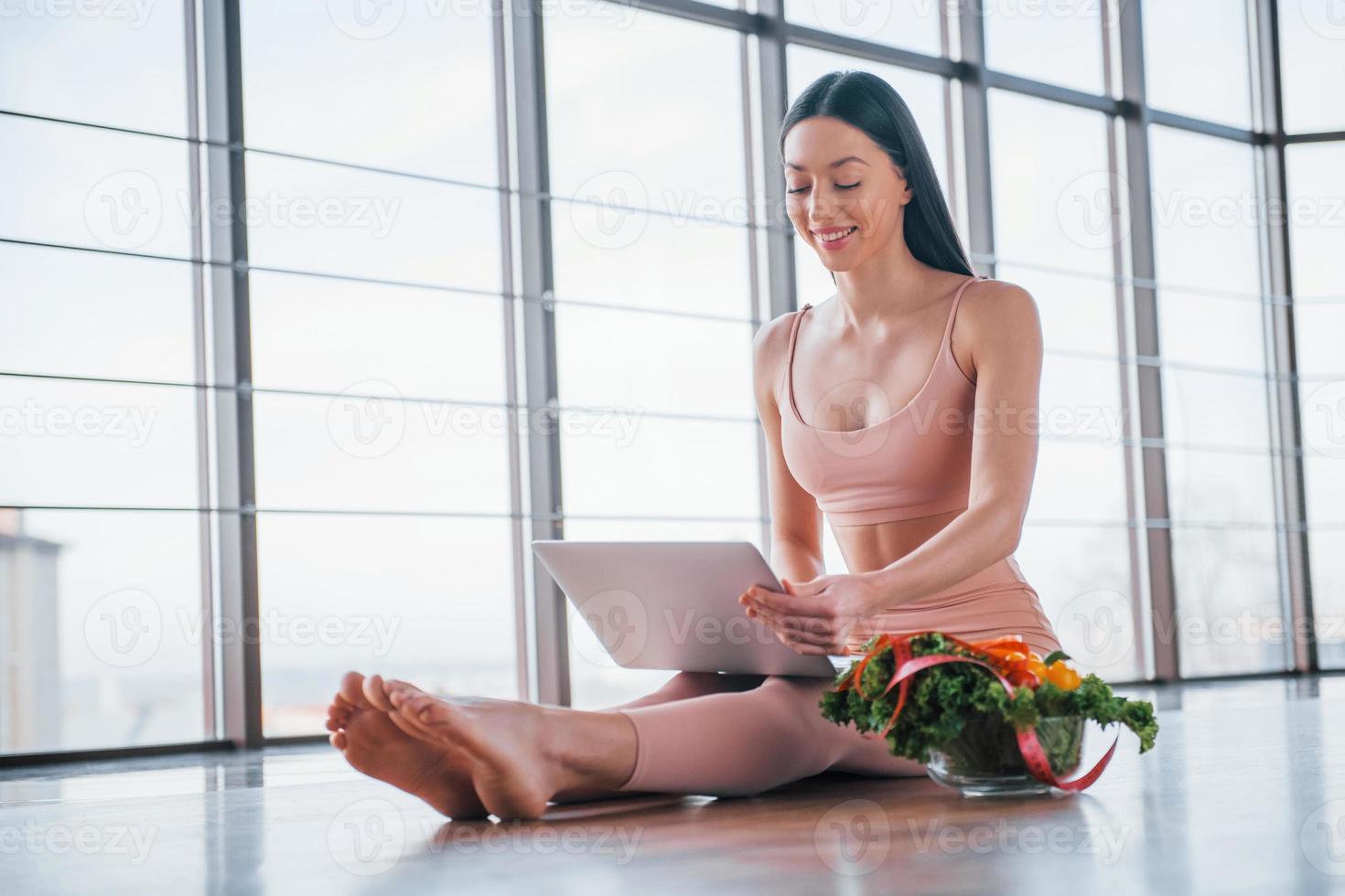 Sportive woman sitting on the table with laptop and healthy food photo