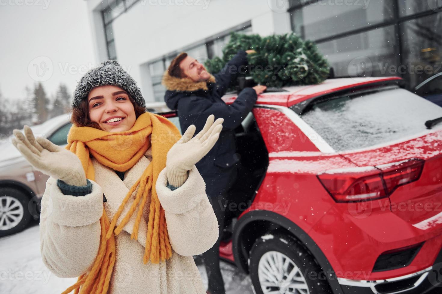 Young couple standing near car with tree on the top. Together outdoors at winter time photo