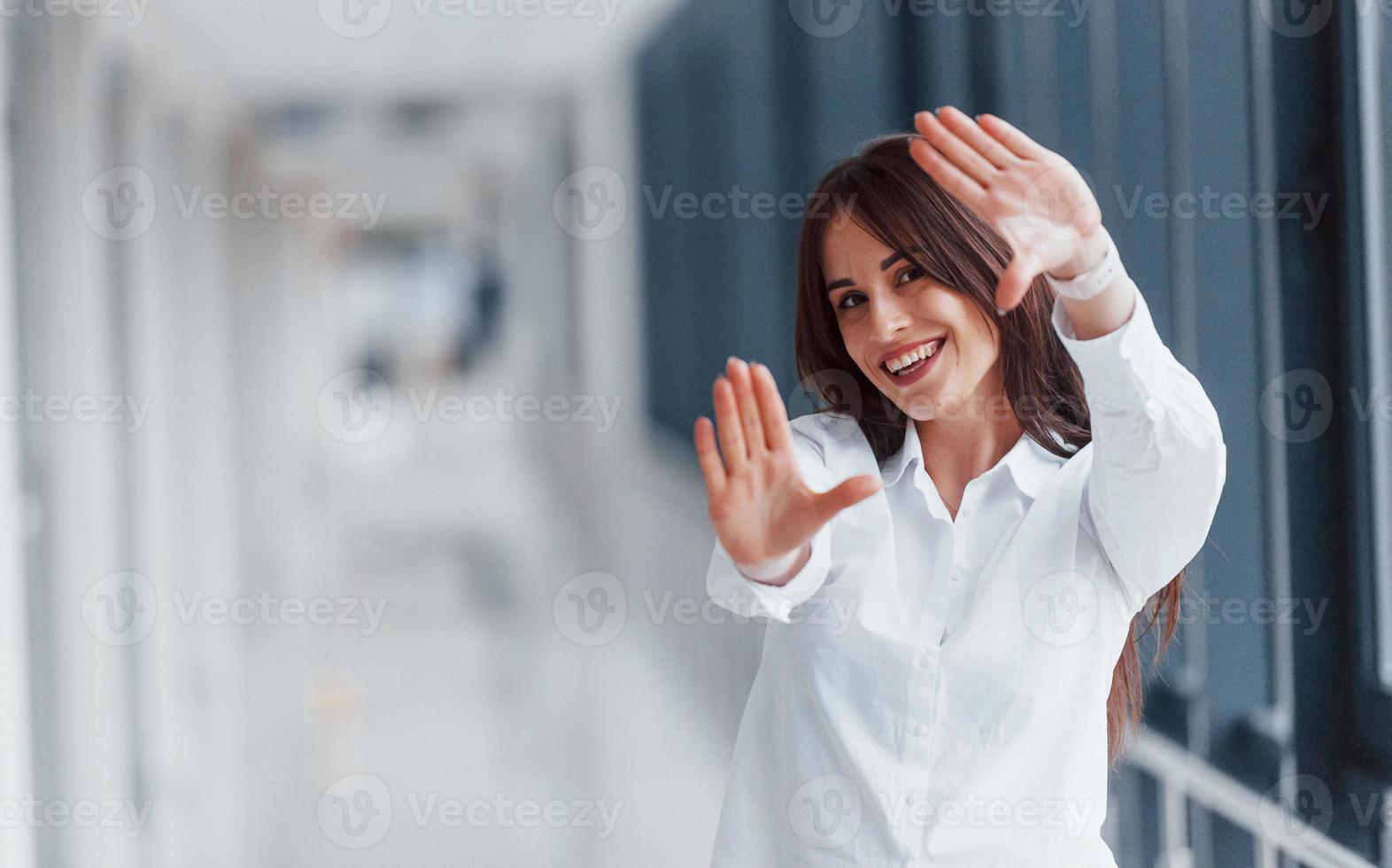 Brunette in white shirt posing indoors in modern airport or hallway at daytime photo