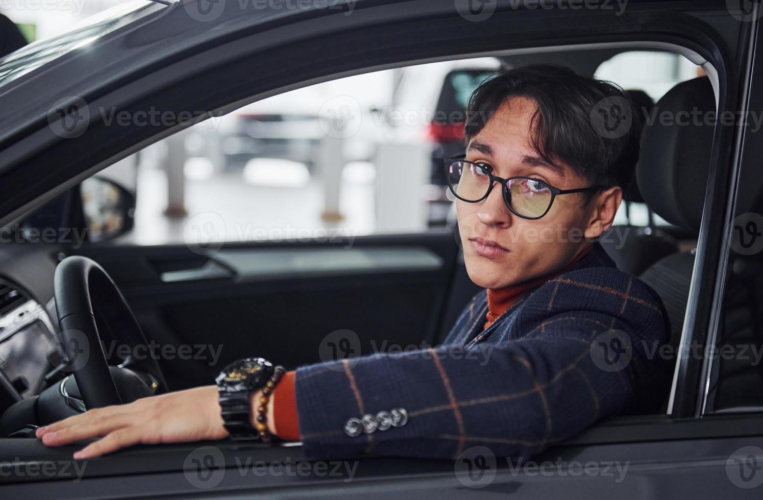 Man in eyewear and formal clothes sitting inside of modern car photo