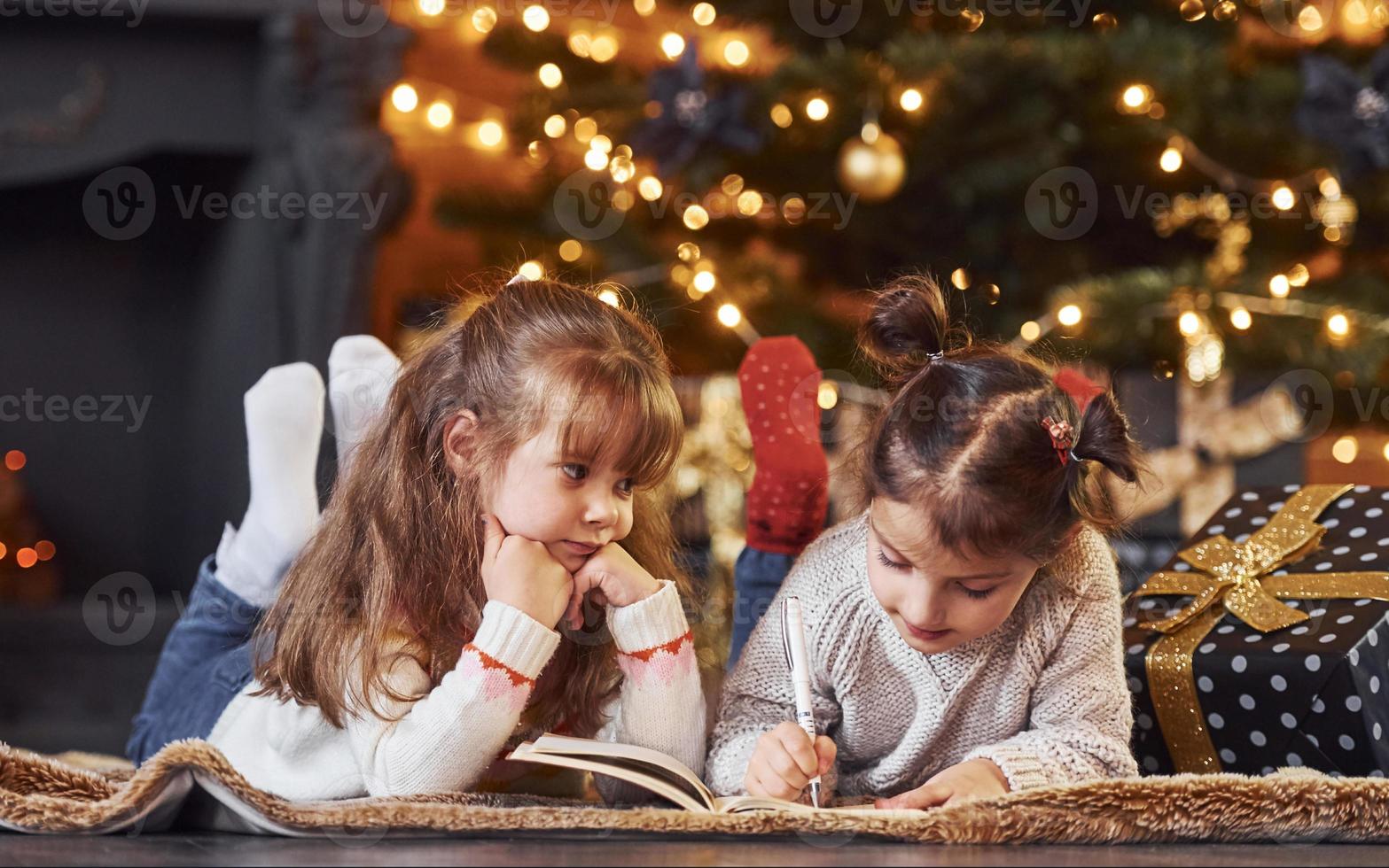 Two little girls have fun in christmas decorated room with gift boxes photo