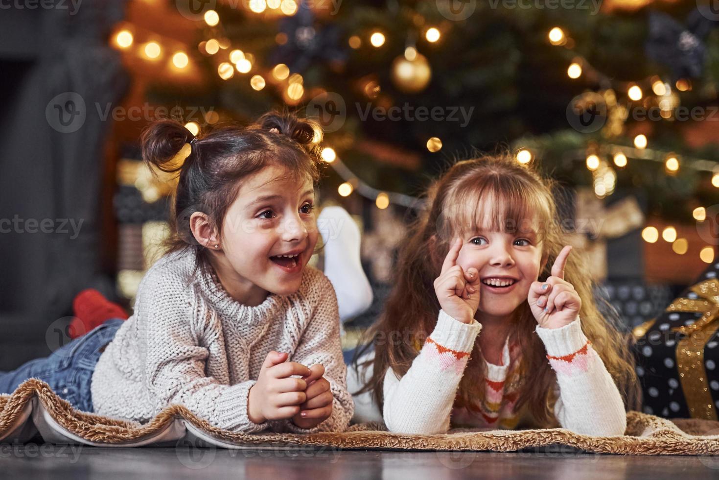 Two little girls have fun in christmas decorated room with gift boxes photo