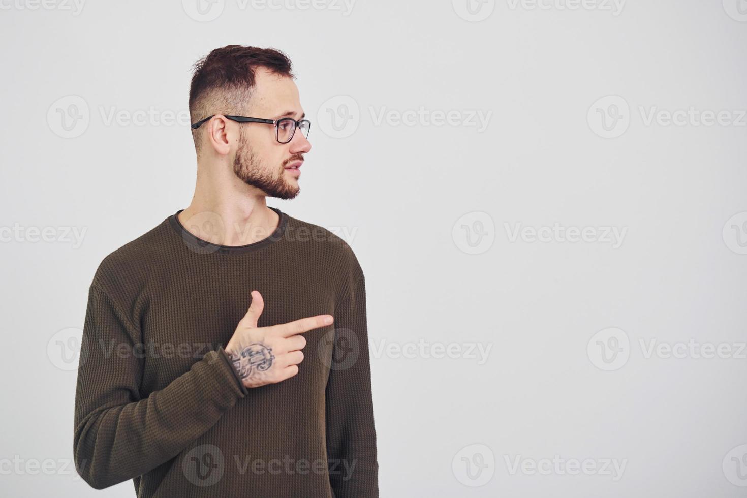 Young guy in sunglasses standing indoors against white background photo