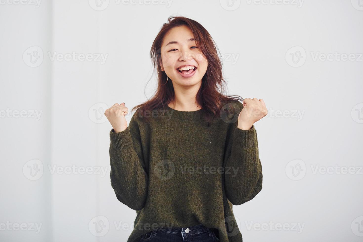 retrato de una joven asiática feliz que está de pie en el interior del estudio con fondo blanco foto