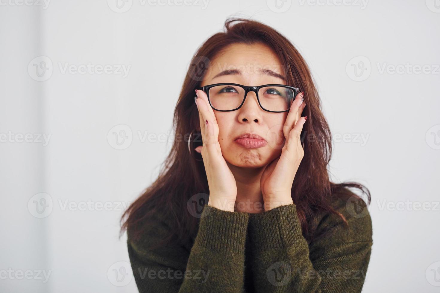 Portrait of happy asian young girl in eyewear that standing indoors in the studio against white background photo