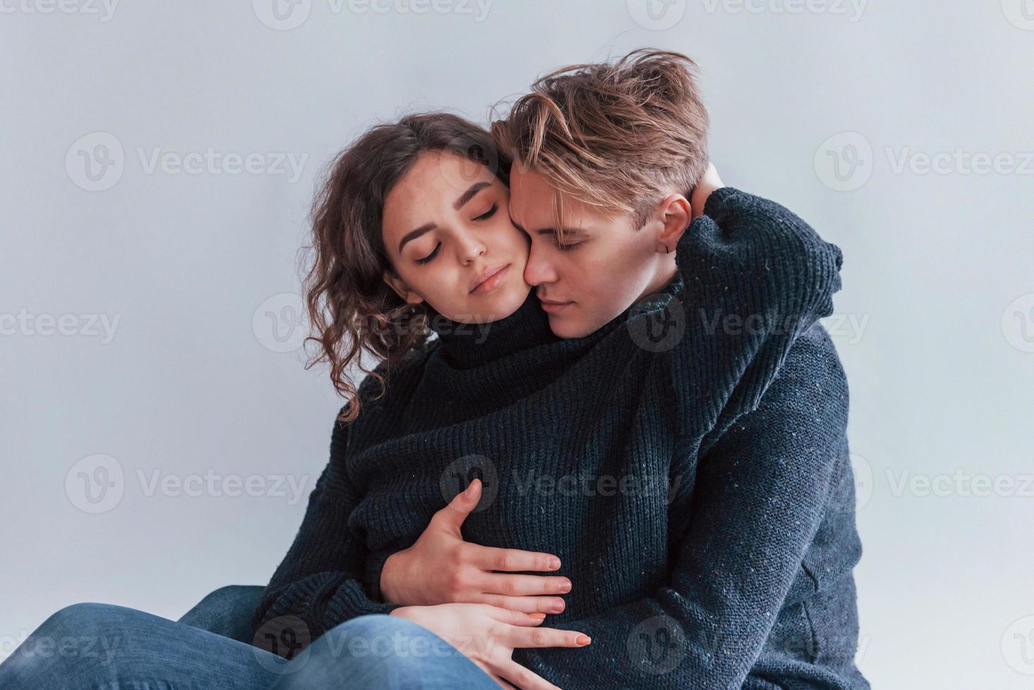 Cute young couple embracing each other indoors in the studio photo