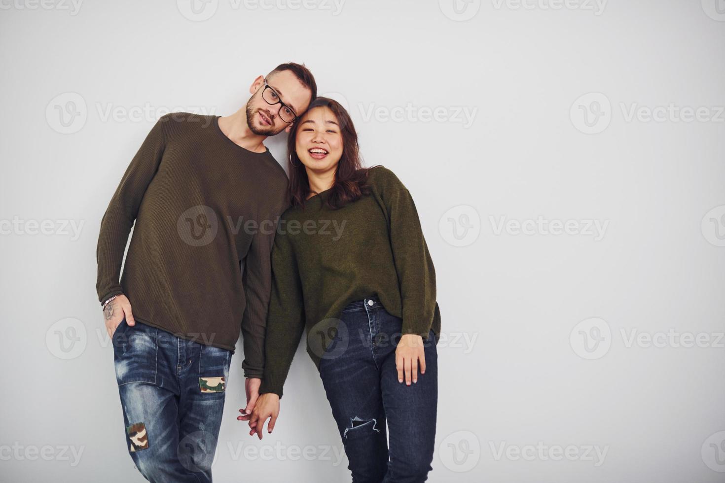 Happy multi ethnic couple in casual clothes is together indoors in the studio. Caucasian guy with asian girlfriend photo