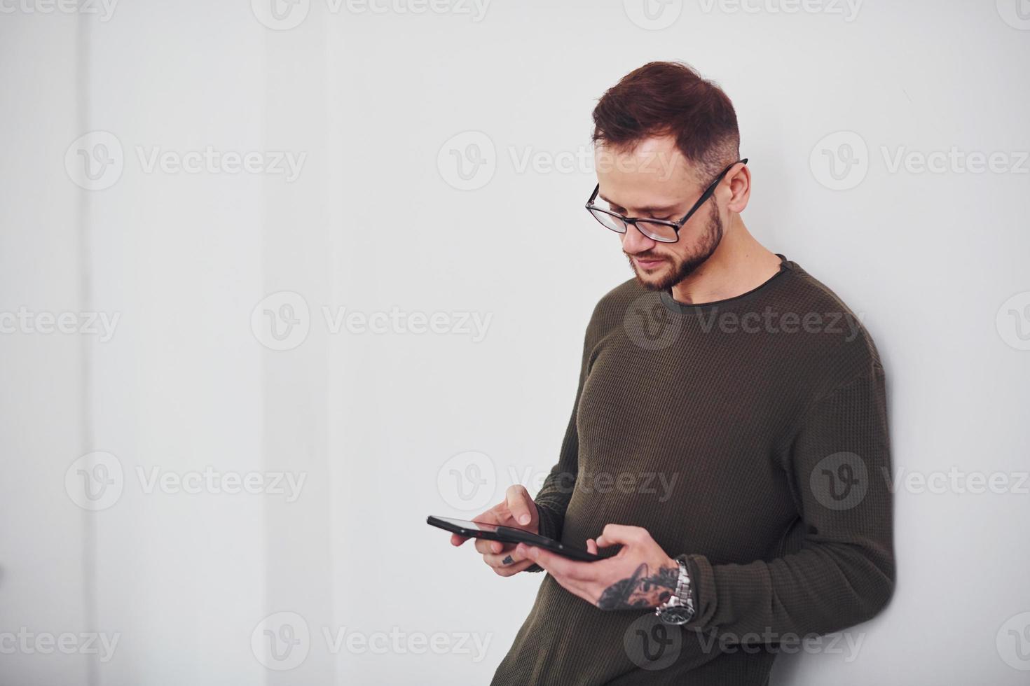 Young guy in sunglasses standing indoors against white background photo