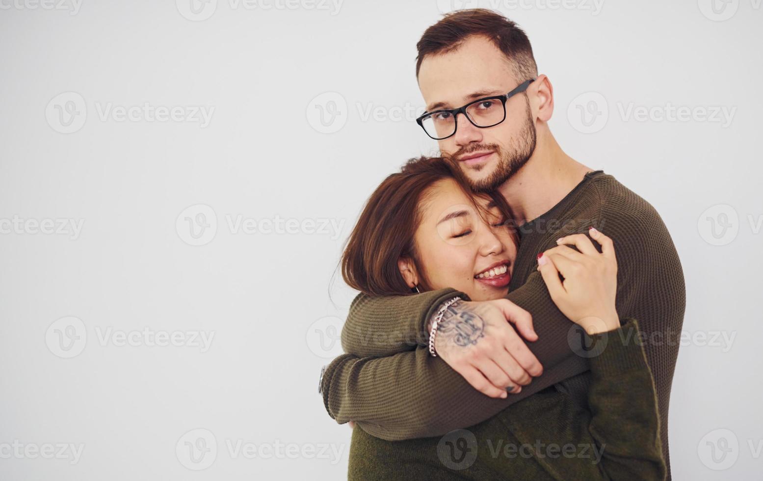 Happy multi ethnic couple in casual clothes is together indoors in the studio. Caucasian guy with asian girlfriend photo
