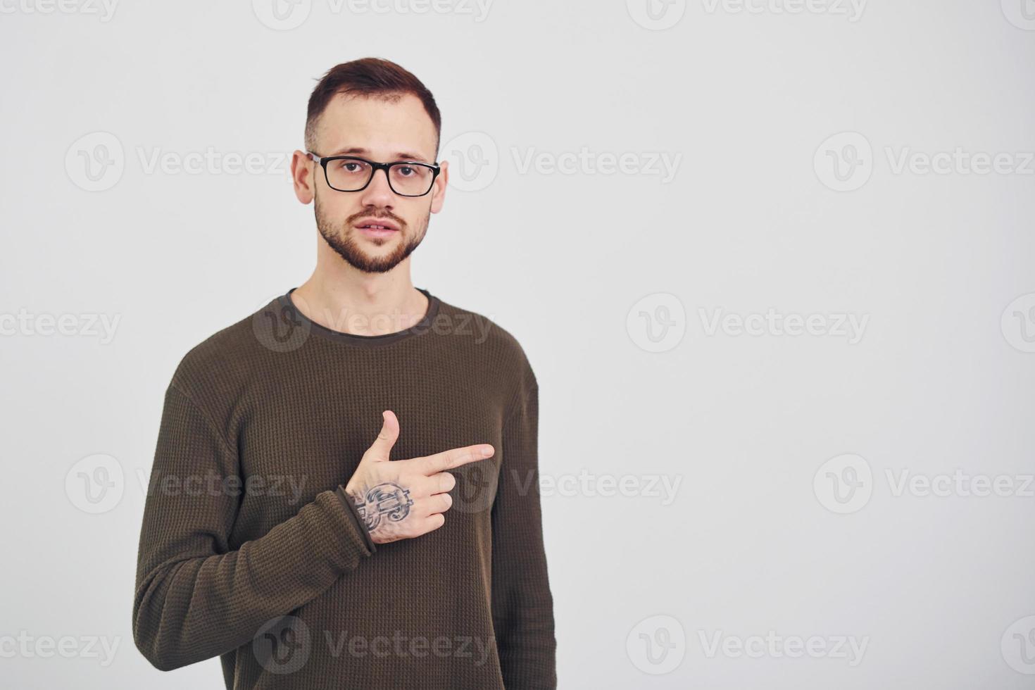 Young guy in sunglasses standing indoors against white background photo