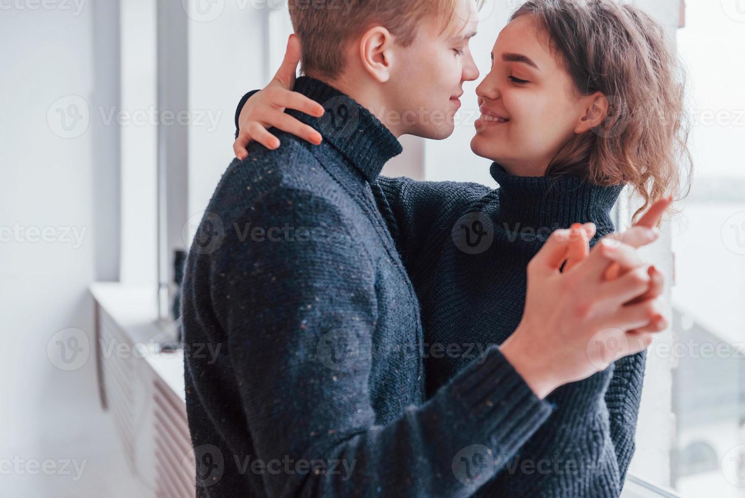 Cute young couple embracing each other indoors near the window photo