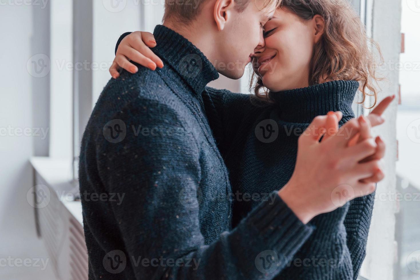 Cute young couple embracing each other indoors near the window photo