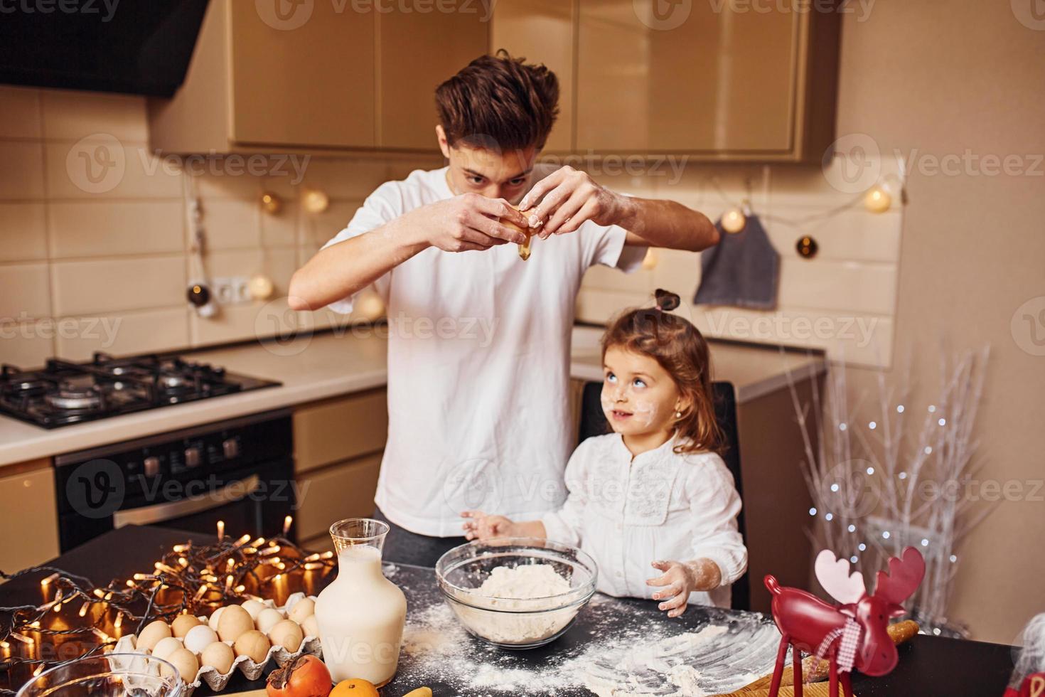 Brother with his little sister preparing food on kitchen and have fun photo