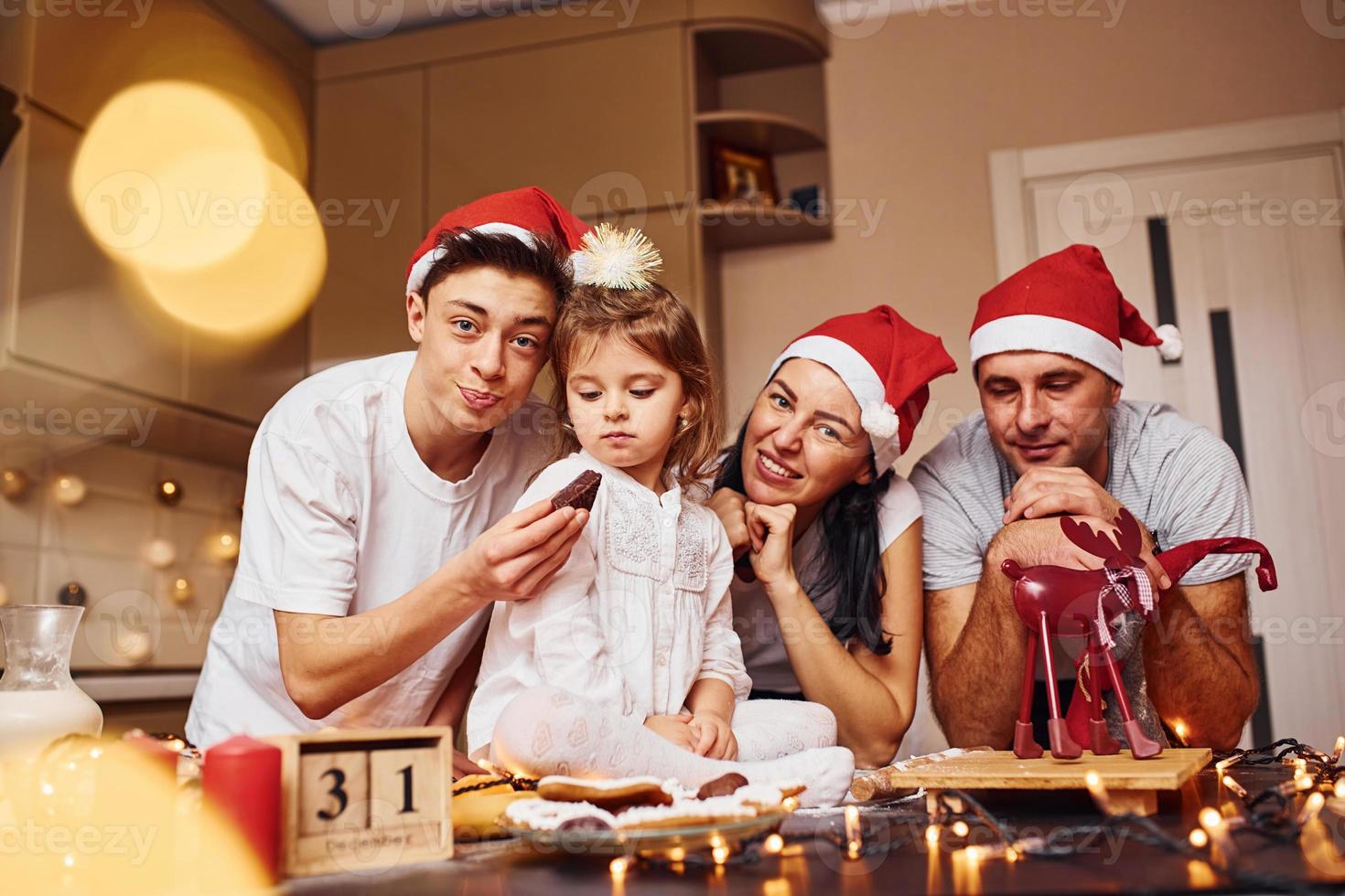 Festive family in christmas hats have fun on the kitchen and preparing food photo