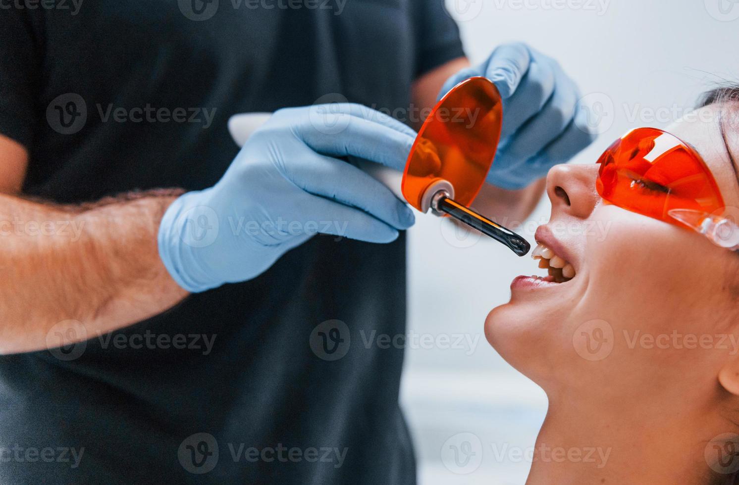 Beautiful woman in red protective glasses have a visit in the dentist clinic. Conception of stomatology photo