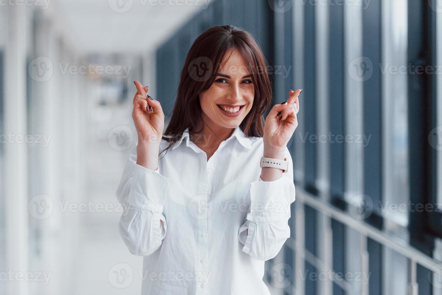 Brunette in white shirt that walks indoors in modern airport or hallway at daytime photo