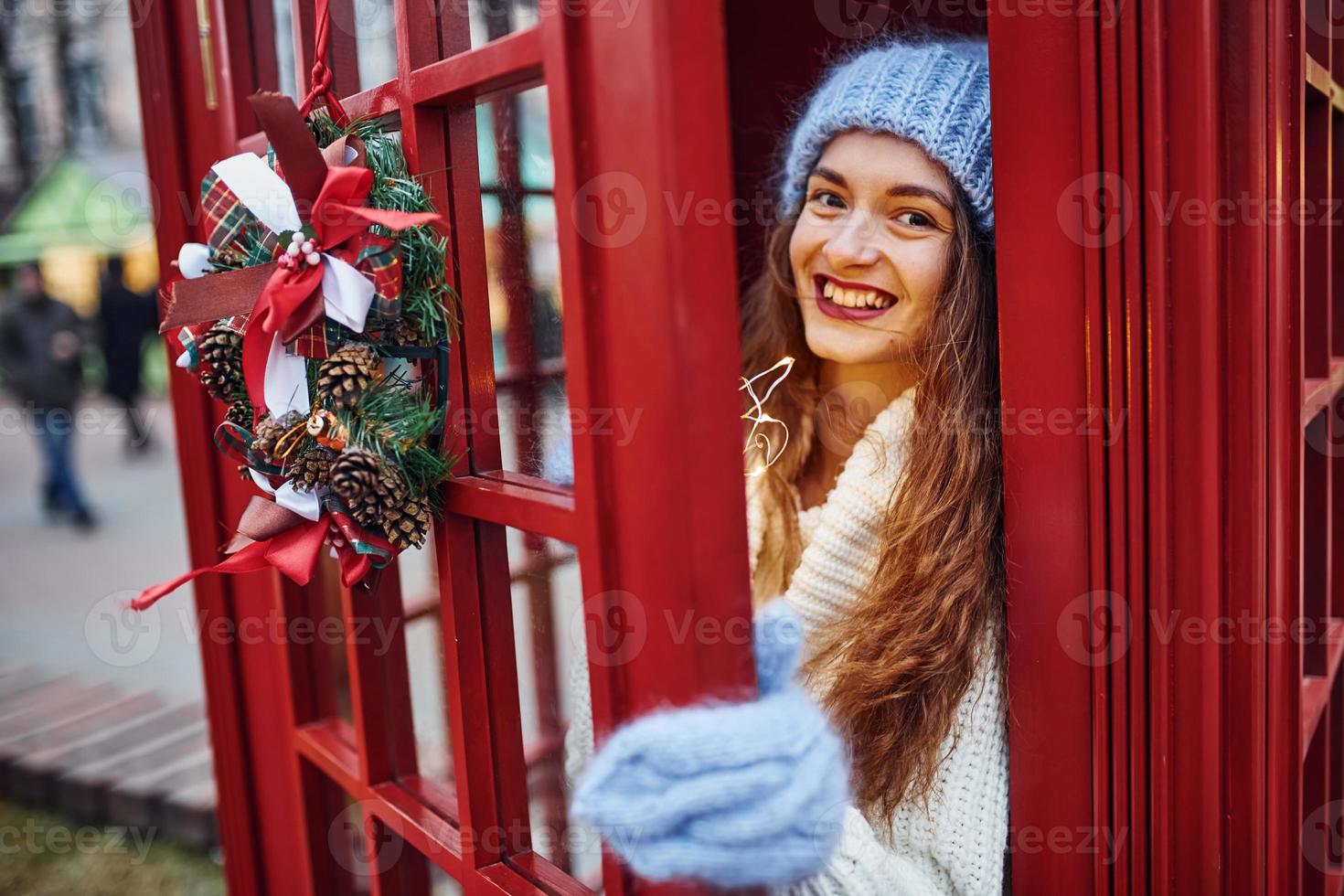 mujer con ropa de abrigo se divierte en la estación telefónica. hermosa chica foto