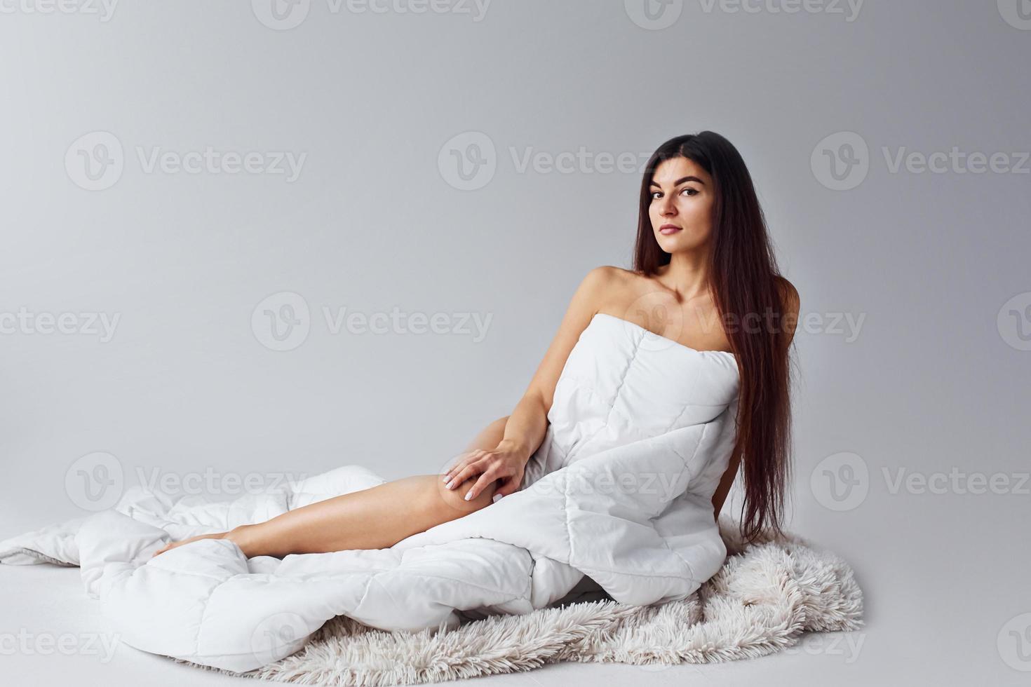 Woman in underwear sits in the studio against white background photo