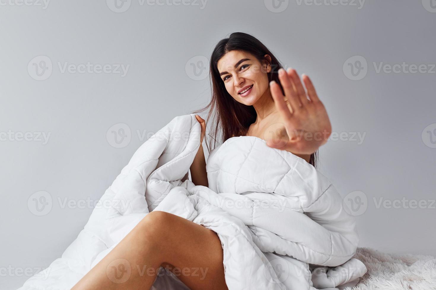 Shows stop gesture. Woman in underwear sits in the studio against white background photo