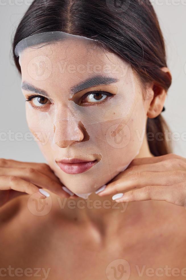 Portrait of woman is in the studio against white background with beauty mask on face photo