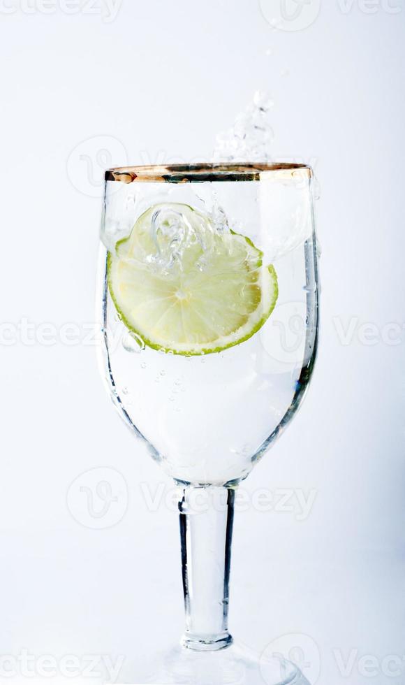 Lime splashing into glass of water photo
